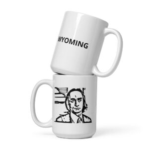 Two stacked white mugs: the top mug reads “WYOMING” in bold black uppercase text; the bottom mug features a black line art portrait of a serious-looking man with long hair in a collared shirt and tie.