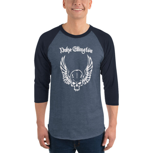 A smiling man wears a dark heather blue and navy 3/4 sleeve raglan shirt featuring a white skull with wings graphic and the words “Duke Ellington” in gothic lettering above.