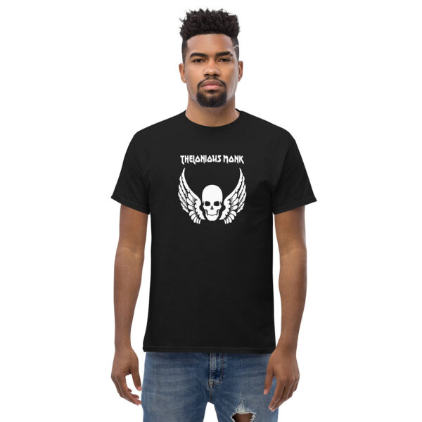 A man wearing a black t-shirt printed with a bold white graphic of a skull with wings, and the words “Thelonious Monk” in a stylized font above the image.