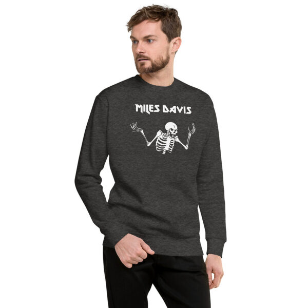 A man in a dark heather gray sweatshirt featuring a white skeleton graphic and “Miles Davis” lettering. He looks to the left with one hand in his pocket.