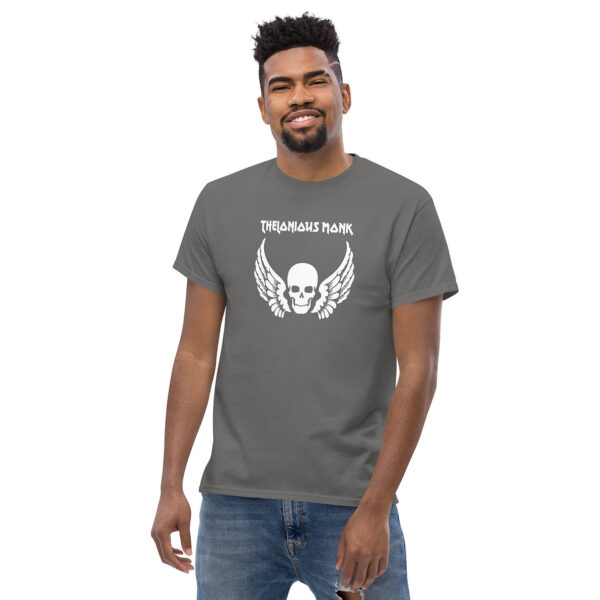 Man smiling in a gray t-shirt printed with a white skull and wings motif, and “Thelonious Monk” in white gothic lettering.
