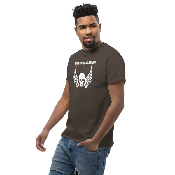 Angled view of a man in a brown t-shirt printed with a white skull and wings graphic and the wordmark “CANNONBALL ADDERLEY.”