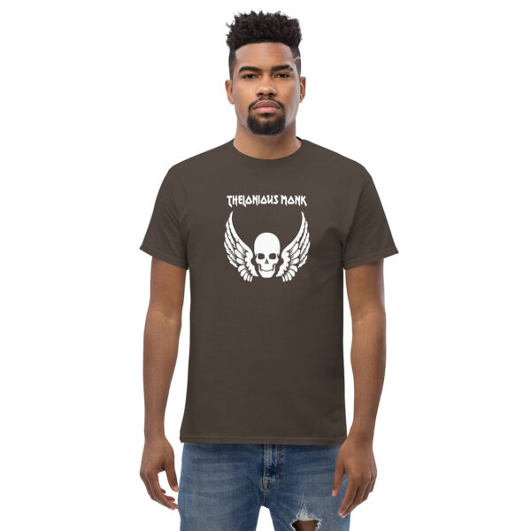 Man modeling a dark brown t-shirt with a white skull and wings image and “Thelonious Monk” text above in distressed block letters.