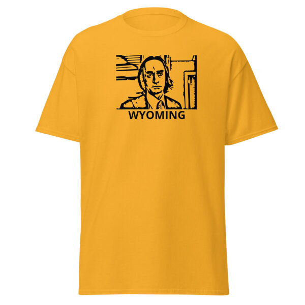 Golden yellow t-shirt showing a black block-print-style illustration of a serious man in a suit and tie within a rectangular border, with the word “WYOMING” centered below.