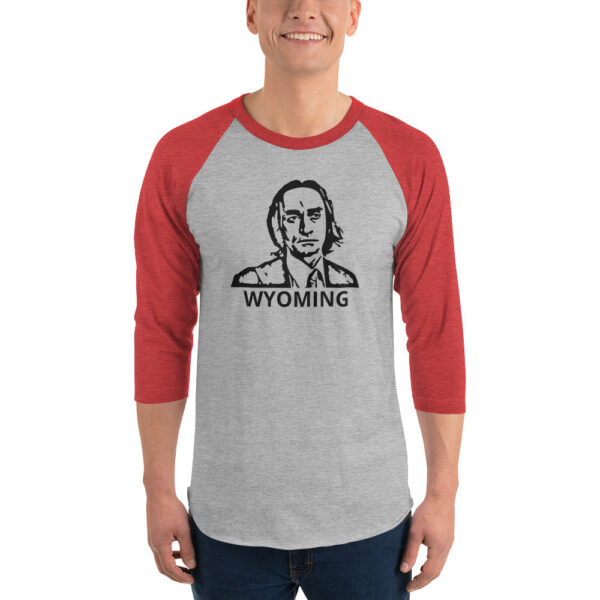 A man wears a heather gray and red 3/4 sleeve raglan shirt with a black stencil-style face illustration and the word "WYOMING" underneath.