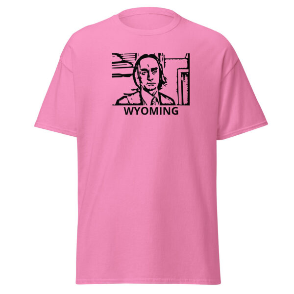 Pink t-shirt showing a black block-print-style illustration of a serious man in a suit and tie within a rectangular border, with the word “WYOMING” centered below.