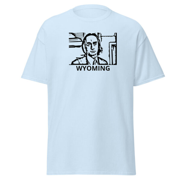 Light blue t-shirt showing a black block-print-style illustration of a serious man in a suit and tie within a rectangular border, with the word “WYOMING” centered below.