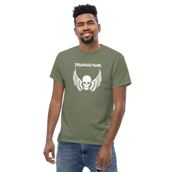Man smiling in an olive green t-shirt with a white skull and wings graphic, and “Thelonious Monk” in stylized font above.