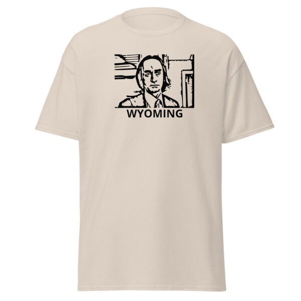 natural off white colored t-shirt showing a black block-print-style illustration of a serious man in a suit and tie within a rectangular border, with the word “WYOMING” centered below.