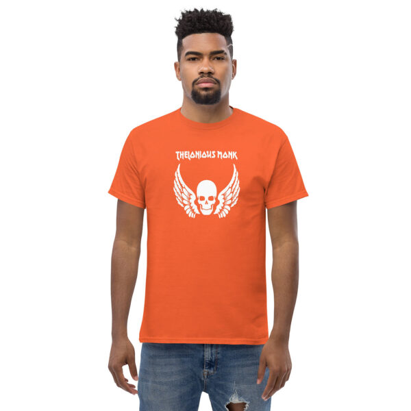 Man in orange t-shirt with white skull and feathered wings graphic, with "THELONIOUS MONK" above in angular capital letters.