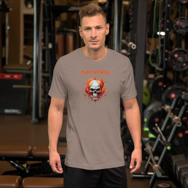 Man in a light gray t-shirt featuring a flaming skull design with "Max Roach" written in red gothic letters, posing in a gym.