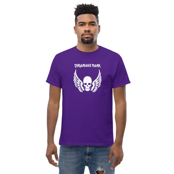 A man wearing a purple t-shirt featuring a white skull with large feathered wings and the name "Thelonious Monk" in stylized white lettering above the graphic.