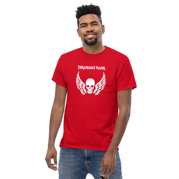 Man smiling in a red t-shirt printed with a white winged skull graphic and “Thelonious Monk” in white stylized text above.