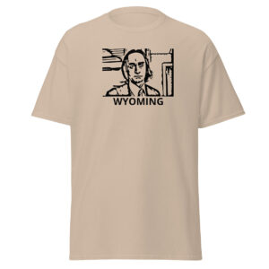 Khaki beige t-shirt featuring a black stencil-style portrait of a solemn man in a collared shirt and tie, enclosed in a boxy outline, with “WYOMING” in black capital letters below.