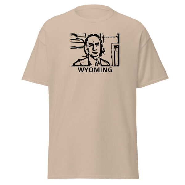 Khaki beige t-shirt featuring a black stencil-style portrait of a solemn man in a collared shirt and tie, enclosed in a boxy outline, with “WYOMING” in black capital letters below.