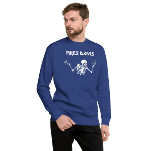 A man in a royal blue crewneck sweatshirt printed with a white skeleton and the name “Miles Davis” above it. He looks slightly to the left with one hand in his pocket.