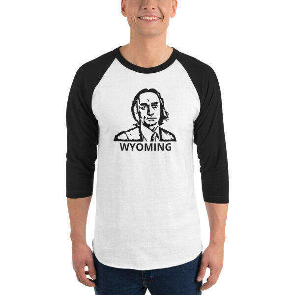 A man wears a white raglan shirt with black 3/4 sleeves featuring a bold black line drawing of a man's face with the word "WYOMING" below.