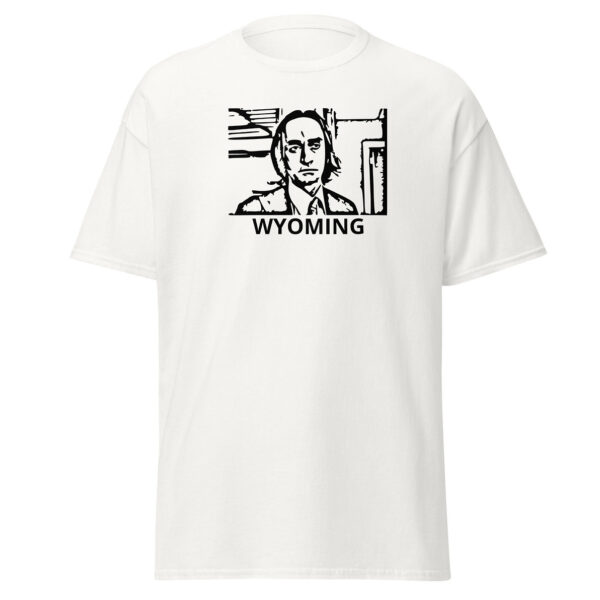 White t-shirt with a bold black line-art portrait of a long-haired man in a jacket and tie, framed in a rectangular outline. Below the image, the word “WYOMING” appears in uppercase sans-serif lettering.