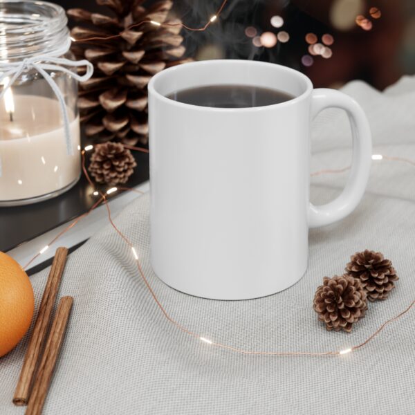 Blank white ceramic coffee mug with steam rising, placed on a cozy holiday-themed setup with a candle, pinecones, cinnamon sticks, orange, and string lights
