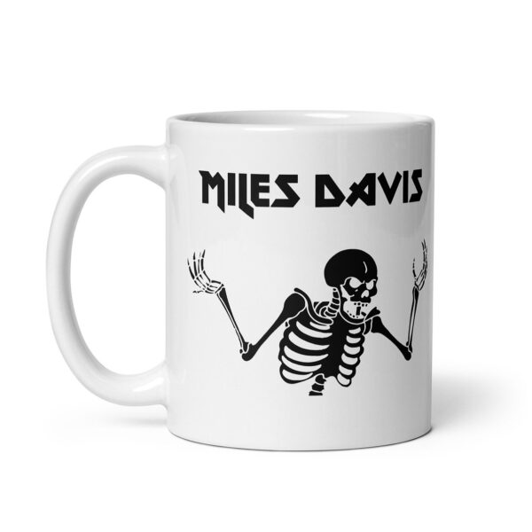 White ceramic mug featuring a black graphic of a skeleton with raised arms and the text "MILES DAVIS" in bold, angular font above the illustration.