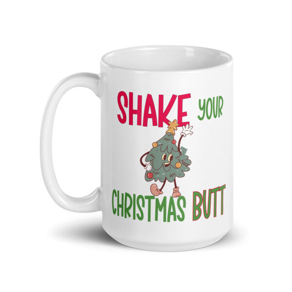 White ceramic mug with a festive design featuring a dancing cartoon Christmas tree and the phrase “SHAKE YOUR CHRISTMAS BUTT” in bold red and green lettering.