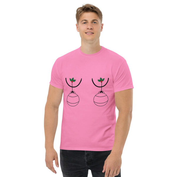 Man wearing a pink T-shirt with a humorous holiday graphic of two Christmas ornaments hanging from holly sprigs, positioned over the chest.