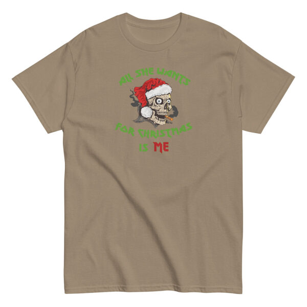 Tan short-sleeve t-shirt with a graphic of a smoking cartoon skull wearing a red Santa hat. The text, in green and red, wraps around the image and reads: "All She Wants For Christmas Is Me."