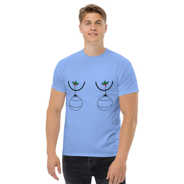 Man wearing a light blue T-shirt featuring a humorous Christmas design with two ornaments hanging from holly sprigs, placed over the chest area.
