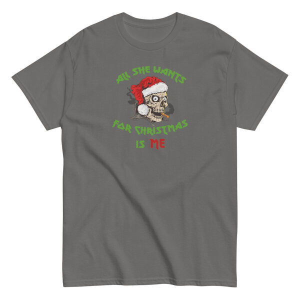 Grey short-sleeve t-shirt featuring a cartoon skull wearing a Santa hat and smoking a cigar. The design includes green and red text reading: "All She Wants For Christmas Is Me," wrapped around the skull illustration.