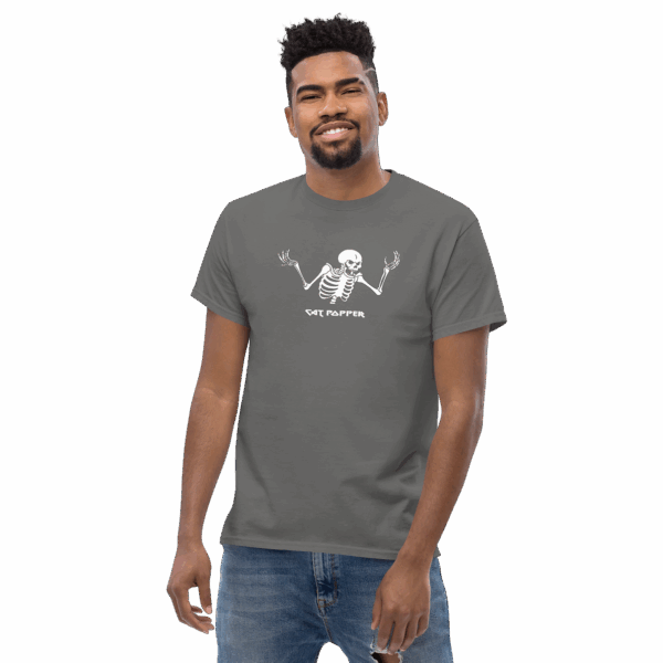 Man wearing a dark gray graphic t-shirt with a white skeleton shrugging and the text "CAT POPPER"; he is smiling and standing casually.