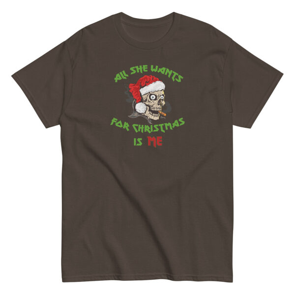 Dark brown short-sleeve t-shirt with a festive design of a cartoon skull wearing a Santa hat and smoking a cigar. Above and below the skull, green and red lettering reads: "All She Wants For Christmas Is Me."