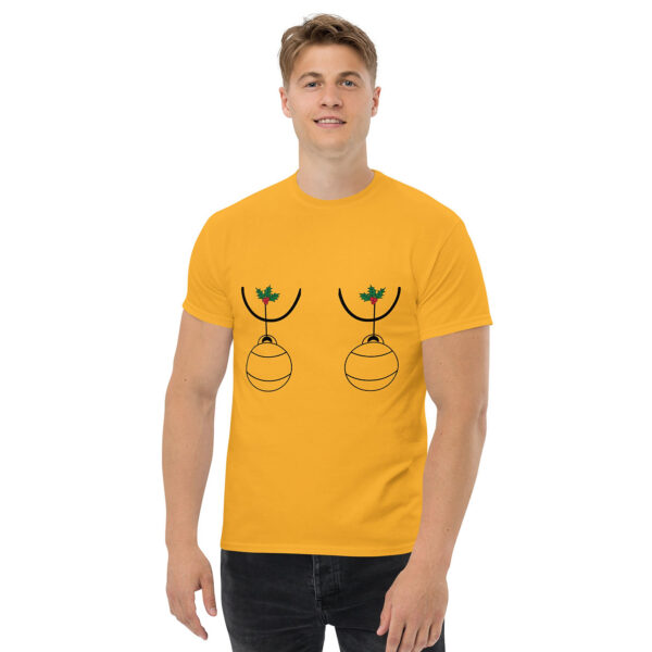 Man wearing a gold T-shirt with a humorous holiday graphic of two Christmas ornaments hanging from holly sprigs, positioned over the chest.
