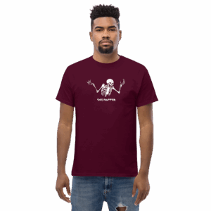 Man in a maroon graphic T-shirt displaying a white skeleton with raised hands and the words "Cat Popper" beneath the design, standing straight with a neutral expression against a plain background.
