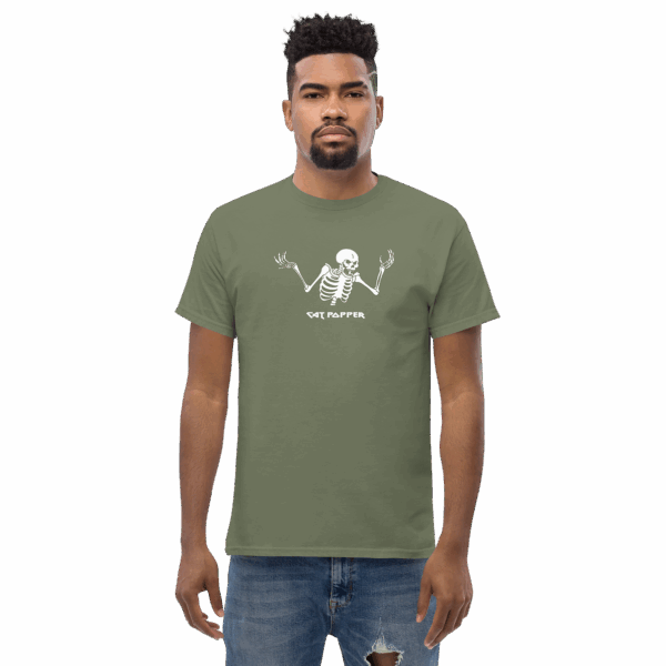 Serious-faced man wearing a moss green T-shirt featuring a white skeleton graphic and the words "Cat Popper" below, standing with arms relaxed at his sides.