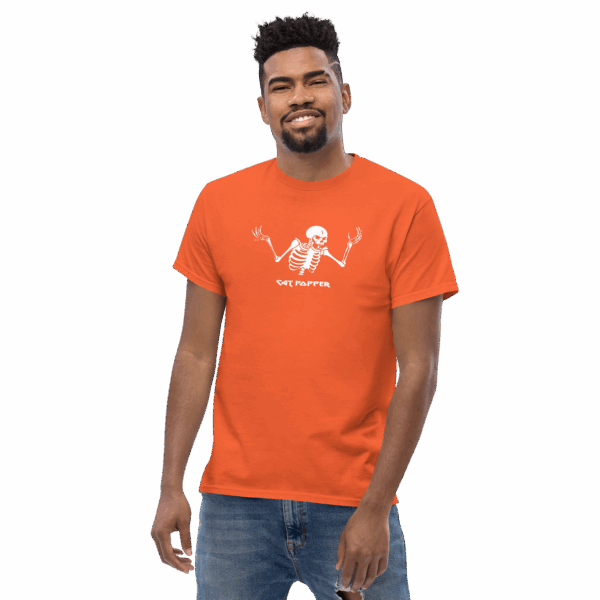 Man wearing a bright orange T-shirt with a white skeleton graphic and the text "CAT POPPER" centered on the chest. He is smiling slightly and standing in a casual pose with his arms relaxed at his sides. The background is transparent.