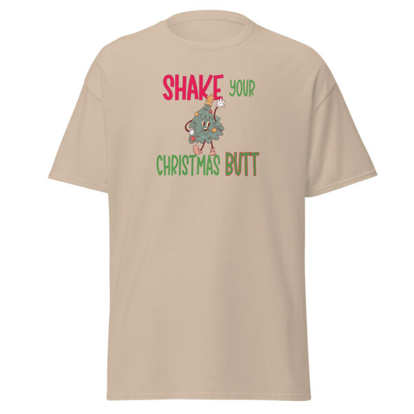Beige short-sleeve t-shirt featuring the phrase "Shake Your Christmas Butt" in festive red, green, and brown lettering, with a cartoon Christmas tree character shaking its hips in the center.