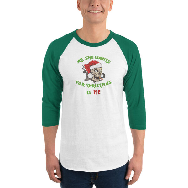 White and green 3/4 sleeve raglan shirt worn by a smiling person. The front features a cartoon skull in a Santa hat, smoking a cigar, with green and red text above and below reading: “All She Wants For Christmas Is Me.”