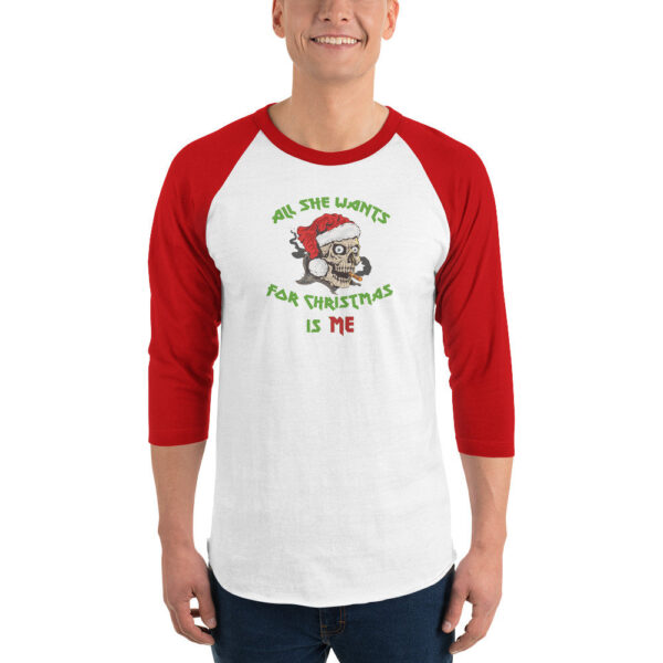 Light heather gray short-sleeve t-shirt featuring a cartoon skull wearing a Santa hat and smoking a cigarette. The graphic is surrounded by green and red text that reads: “All She Wants For Christmas Is Me.”